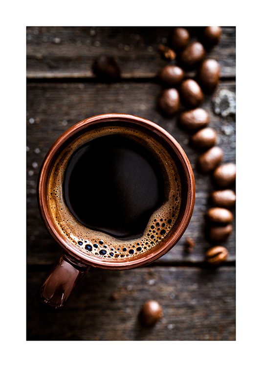  – Fotografie einer Kaffeetasse von oben auf einem Holztisch mit Kaffeebohnen daneben